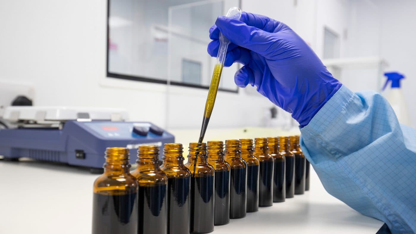 Curaleaf Laboratories — pipetting cannabis oil into amber dispensing bottles in the lab